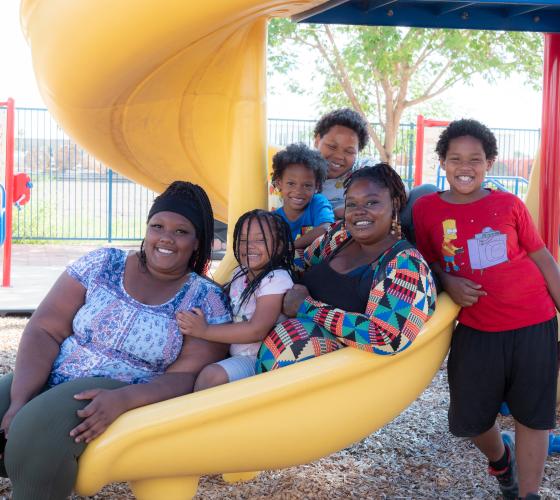 family-campaign Woman and her children sitting on a playground slide