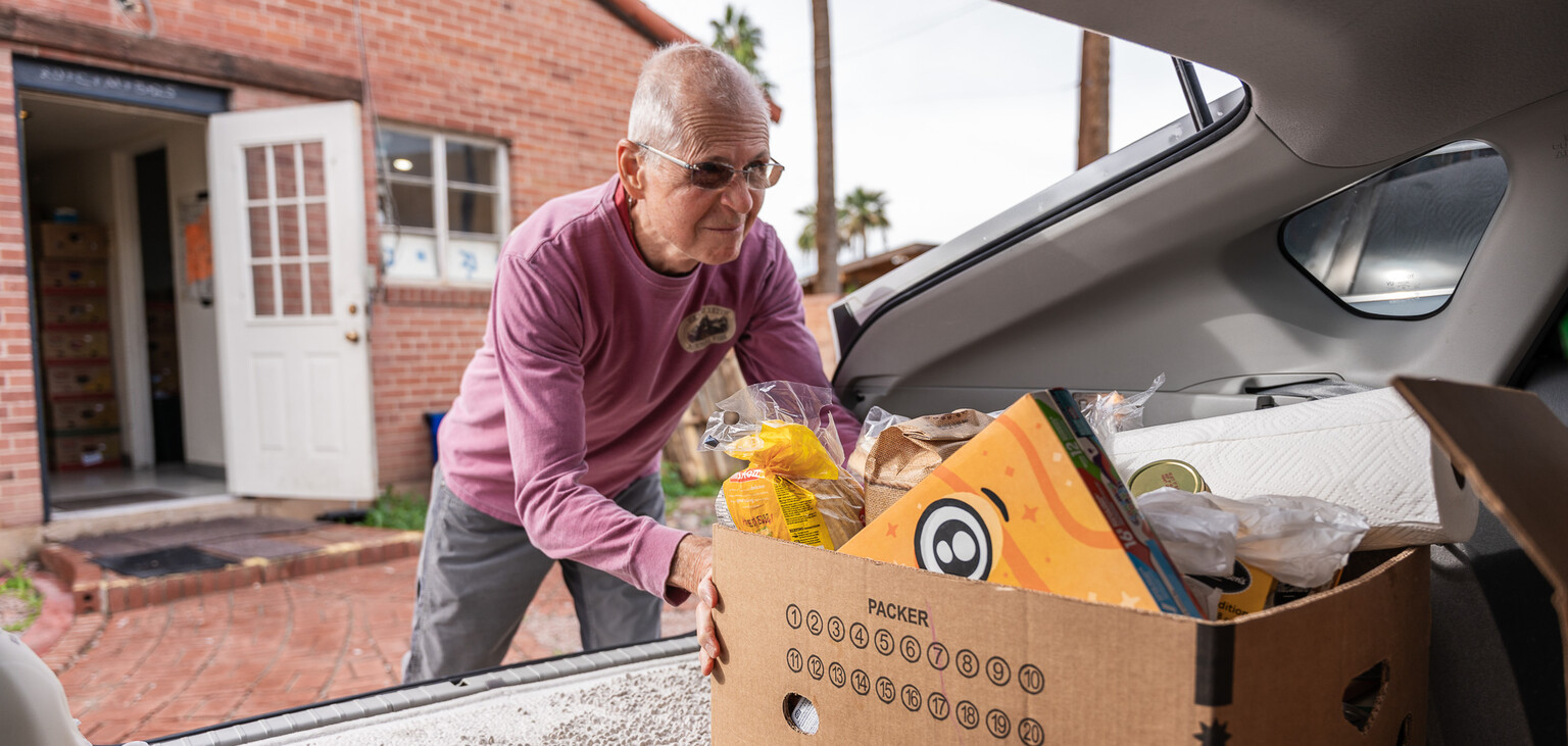 A Vincentian volunteer puts a box of food in their car for delivery to a family in need.