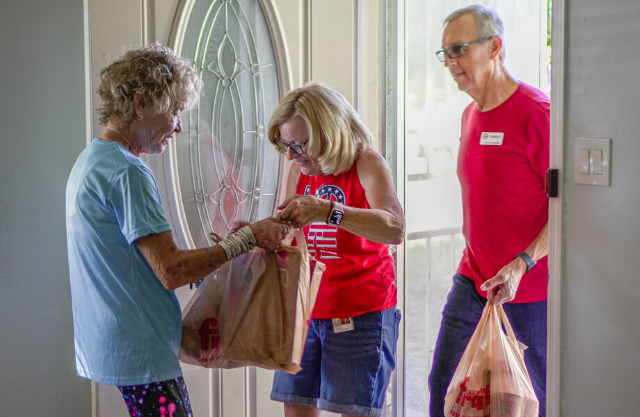 Paula Bishoff receives bags of food from Vincentian volunteers in her doorway.
