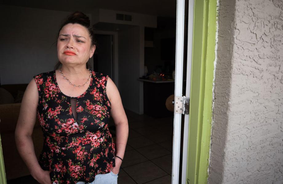 On a recent home visit, a mother affected economically by the COVID-19 pandemic looks worriedly from her doorway, unsure what the future may bring.