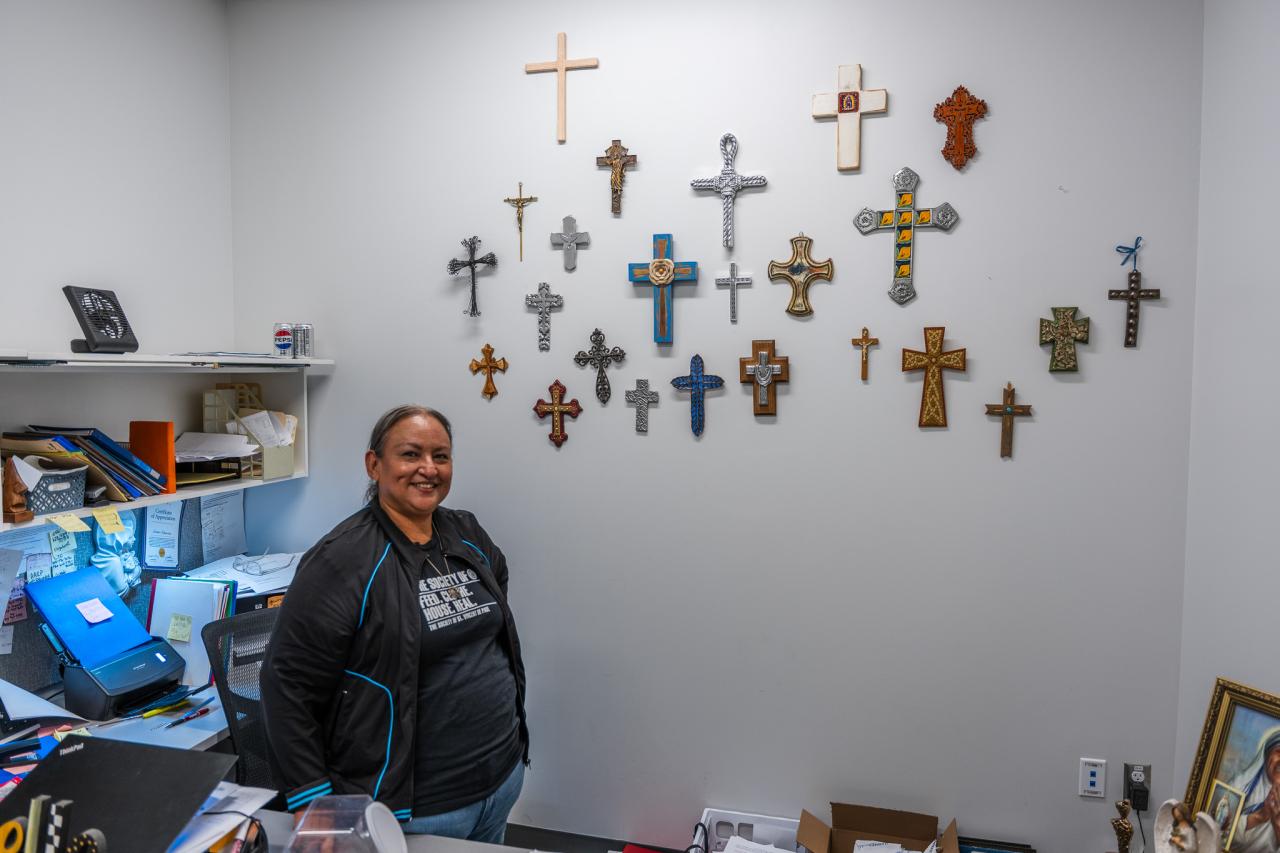 Esther stands by her wall of crosses.