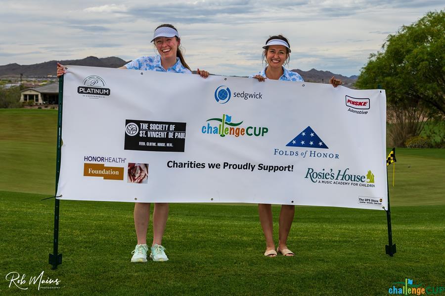 Two SVdP representatives stand behind a banner showing SVdP as a recipient of Challenge Cup's generosity.